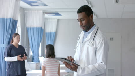 Portrait-of-african-american-male-doctor-using-tablet-and-smiling-in-ward,-copy-space,-slow-motion