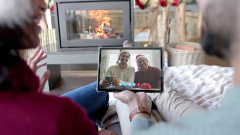 Happy-diverse-couple,-father-and-adult-son-having-christmas-tablet-video-call,-slow-motion