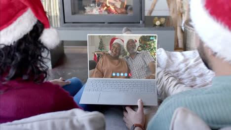 Glückliches,-Vielfältiges-Paar-Und-ältere-Eltern-Mit-Weihnachtlichem-Laptop-Videoanruf,-Zeitlupe