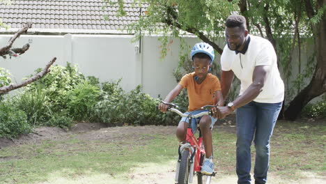 Afroamerikanischer-Vater-Bringt-Seinem-Sohn-Das-Fahrradfahren-Im-Freien-Bei,-Mit-Kopierraum