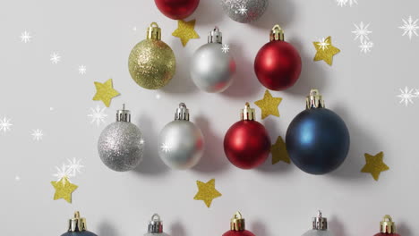 Animation-of-snow-falling-over-christmas-baubles-and-stars