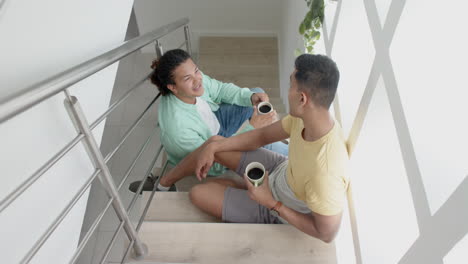 Glückliches,-Heterosexuelles-Paar,-Das-Auf-Einer-Sonnigen-Treppe-Sitzt,-Kaffee-Trinkt-Und-Redet,-Zeitlupe