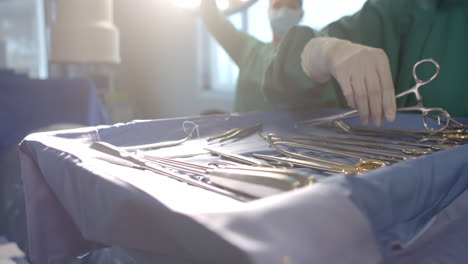 Midsection-of-female-surgeon-preparing-surgical-instruments-in-operating-theatre,-slow-motion