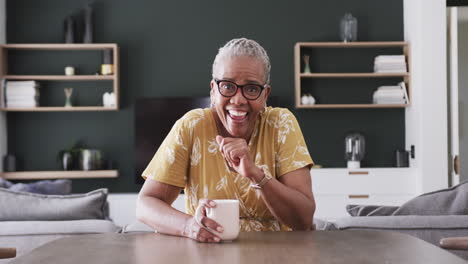 Happy-senior-african-american-woman-in-glasses-having-video-call-at-home-with-coffee,-slow-motion