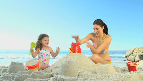 Schöne-Mutter-Hilft-Ihrer-Tochter-Beim-Sandburgenbauen