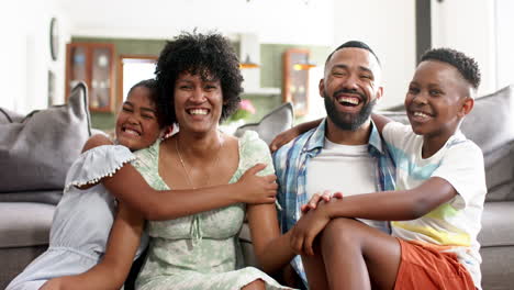 Portrait-of-happy-african-american-parents,-daughter-and-son-embracing-in-living-room,-slow-motion