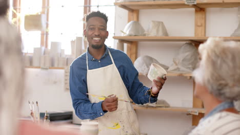 Happy-african-american-potter-working-with-others-in-pottery-studio,-slow-motion