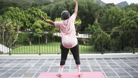 Rear-view-of-senior-african-american-woman-practicing-yoga-on-balcony,-copy-space,-slow-motion