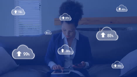Animation-of-cloud-icons-with-growing-number-over-biracial-businesswoman-using-smartphone