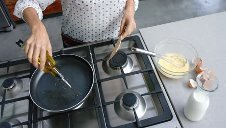 Mujer-Birracial-Cocinando-Y-Vertiendo-Aceite-En-Una-Sartén-En-La-Cocina,-Cámara-Lenta