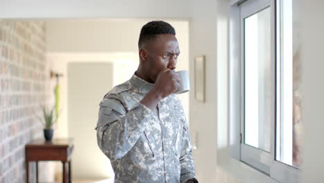 Young-African-American-soldier-holding-a-coffee-mug-at-home,-with-copy-space