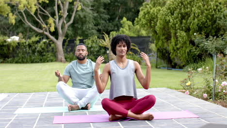 Fokussiertes-Afroamerikanisches-Paar,-Das-Yoga-Meditation-Im-Garten-Praktiziert,-Zeitlupe