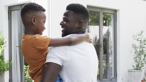 African-American-man-embraces-a-joyful-boy-at-home