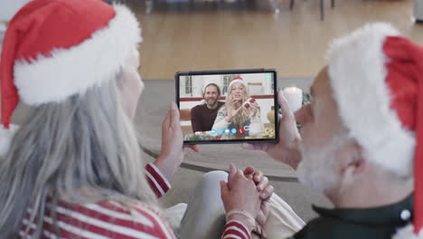 Happy-caucasian-couple-and-senior-parents-having-christmas-tablet-video-call,-slow-motion