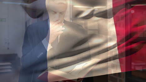 Animation-of-flag-of-france-waving-over-caucasian-businessman-studying-book-in-library