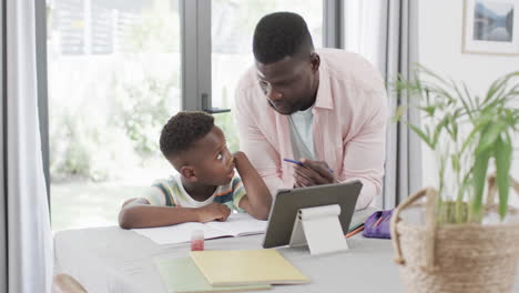 African-American-man-helps-a-boy-with-homework-at-home-using-a-tablet