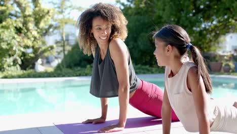 Happy-biracial-mother-and-daughter-practicing-yoga-in-sunny-garden,-copy-space,-slow-motion