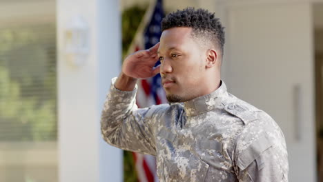 Glücklicher-Afroamerikanischer-Soldat,-Der-Zu-Hause-über-Der-Flagge-Der-USA-Salutiert,-Zeitlupe