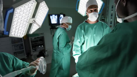 Diverse-male-and-female-surgeons-operating-on-patient-in-operating-theatre-at-hospital,-slow-motion