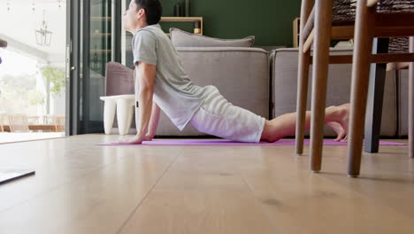 Fokussierter-Biracial-Mann,-Der-Yoga-Praktiziert,-Im-Wohnzimmer-Liegend,-Zeitlupe