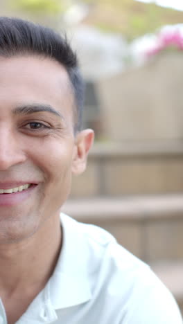 Vertical-video-half-portrait-of-happy-biracial-man-smiling-in-sunny-garden,-slow-motion