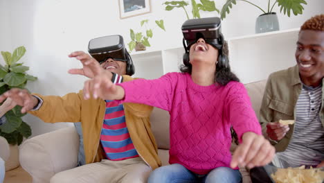 Happy-diverse-group-of-teenage-friends-with-snacks-playing-with-vr-headsets-at-home,-slow-motion