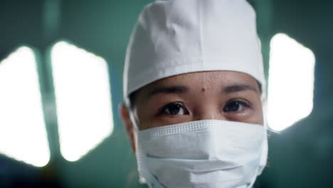Porträt-Einer-Asiatischen-Chirurgin-Mit-Gesichtsmaske-Im-Operationssaal-Eines-Krankenhauses,-Zeitlupe