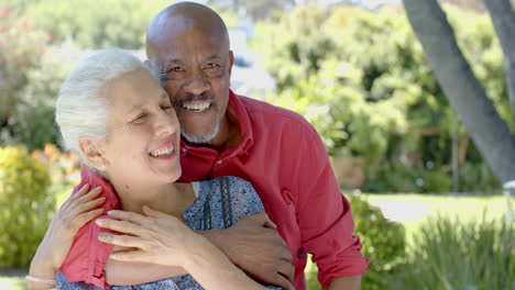 Portrait-of-happy-senior-biracial-couple-embracing-in-sunny-garden-at-home,-slow-motion