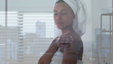 Animation-of-biracial-woman-wearing-towel-on-head-over-cityscape