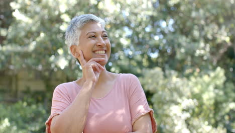 Portrait-of-happy-senior-biracial-woman-with-short-hair-in-sunny-garden-at-home,-slow-motion
