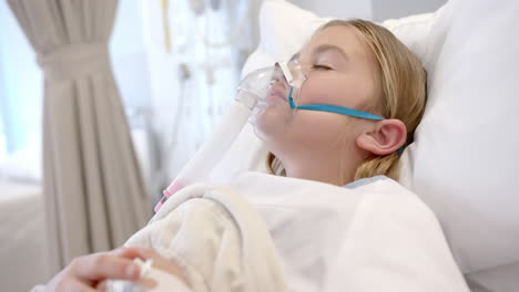 Caucasian-girl-patient-in-oxygen-mask-asleep-in-hospital-bed,-slow-motion