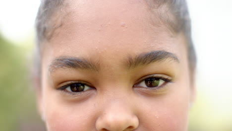 Porträt-Aus-Braunen-Augen-Eines-Glücklichen-Afroamerikanischen-Mädchens,-Das-Im-Sonnigen-Garten-Lächelt,-Zeitlupe