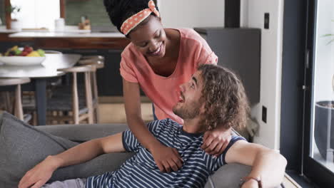 Diverse-couple,-a-young-African-American-woman-and-Caucasian-man,-share-a-moment-at-home