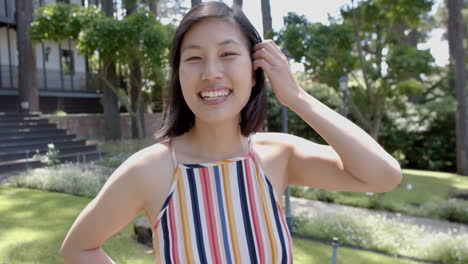 Happy-asian-woman-with-dark-straight-hair-standing-and-smiling-in-sunny-garden,-slow-motion