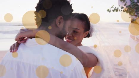 Animation-Von-Lichtpunkten-über-Einem-Afroamerikanischen-Paar,-Das-Am-Strand-Heiratet