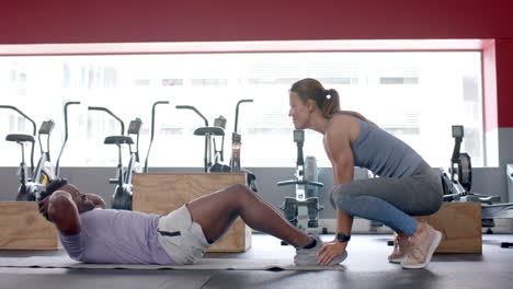 Fit-young-Caucasian-woman-assists-African-American-man-during-a-workout-at-the-gym