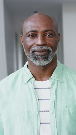 Vertical-video-of-portrait-of-happy-biracial-man-with-gray-beard-at-home,-slow-motion