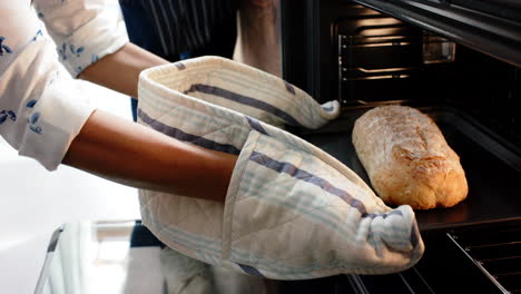 Biracial-woman-wearing-apron-and-baking-bread-in-kitchen,-slow-motion