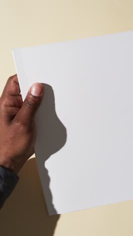 Vertikales-Video-Der-Hand-Eines-Afroamerikanischen-Mannes-Mit-Einem-Buch-Mit-Weißen-Leeren-Seiten-Auf-Weißem-Hintergrund
