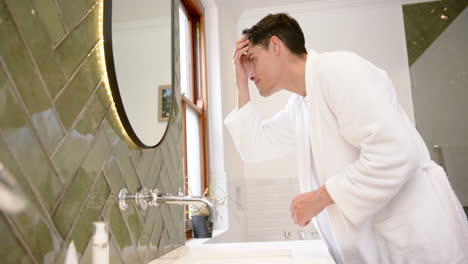 Fokussierter-Biracial-Mann-Inspiziert-Haare-Und-Gesicht-Im-Badezimmerspiegel,-Kopierraum,-Zeitlupe