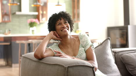 Portrait-of-happy-african-american-woman-on-sofa-in-sunny-living-room,-copy-space,-slow-motion