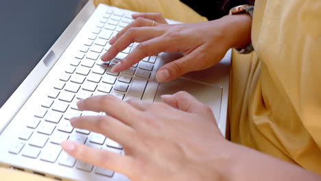 Hands-of-biracial-teenage-girl-using-laptop-keyboard,-slow-motion