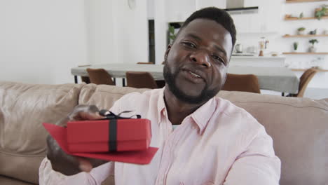 African-American-man-offering-a-gift-at-home-on-a-video-call