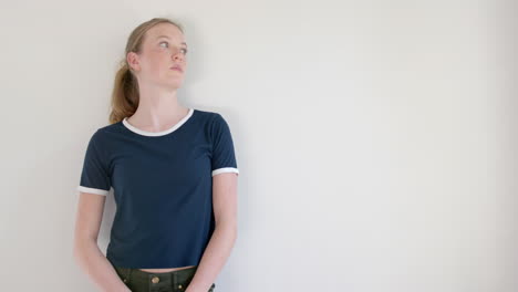 Caucasian-woman-in-navy-blue-t-shirt-with-white-edging,-against-white-wall,-copy-space,-slow-motion