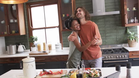 Diverse-couple,-a-young-African-American-woman-and-a-young-Caucasian-man,-embrace-in-a-home-kitchen