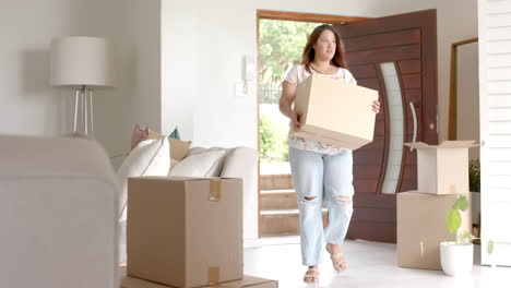 Happy-plus-size-biracial-woman-carrying-box,-moving-into-new-home,-copy-space,-slow-motion