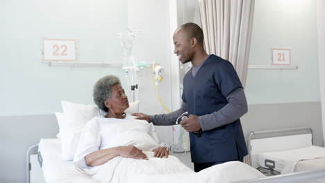 Feliz-Médico-Afroamericano-Hablando-Con-Una-Paciente-Mayor-En-La-Habitación-Del-Hospital,-Cámara-Lenta