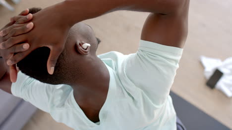 Focused-african-american-man-stretching-in-sunny-living-room,-slow-motion