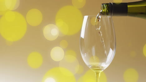 Komposit-Aus-Weißwein,-Der-In-Ein-Glas-über-Gelbe-Flecken-Gegossen-Wird