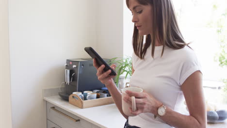 Middle-aged-Caucasian-woman-checks-her-phone-at-home,-with-copy-space